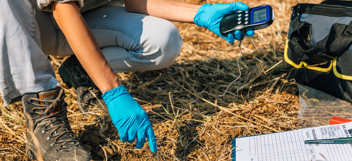 Measuring Soil Temperature with Thermometer. Female agronomist measuring soil temperature in the field. Field work for Environment protection project